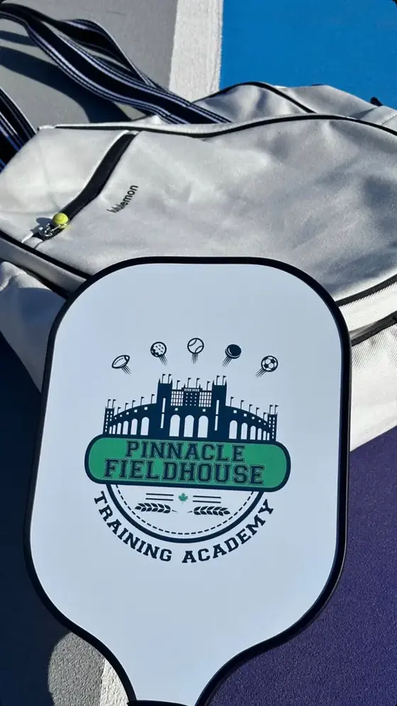Close-up of a white academy crest pickleball paddle on a court bag