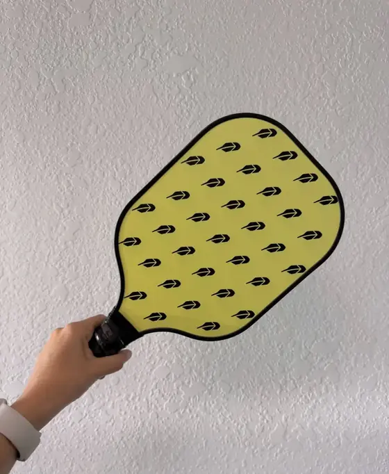 Custom yellow pickleball paddle with an all-over arrow logo pattern