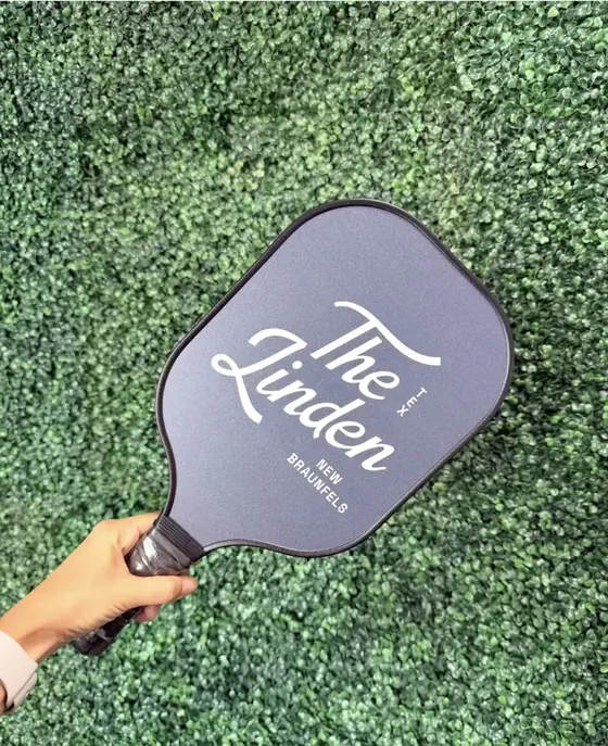 Charcoal pickleball paddle printed with The Linden hotel script logo