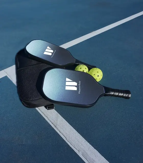 Two black realty-branded pickleball paddles with a sling bag and balls