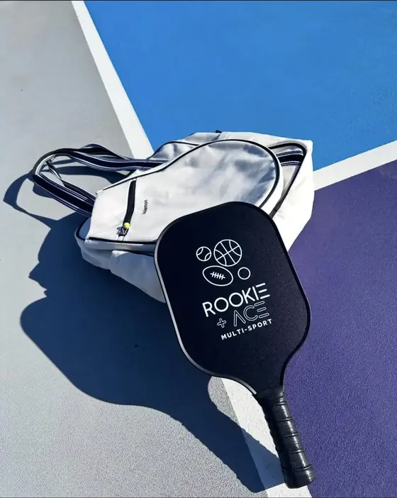Black Rookie and Ace multi-sport pickleball paddle on a court tote bag