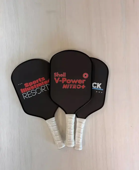 Three black custom pickleball paddles printed for Sports Illustrated Resorts and Shell V-Power